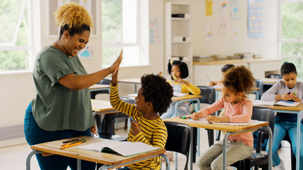 educator high fives student in classroom